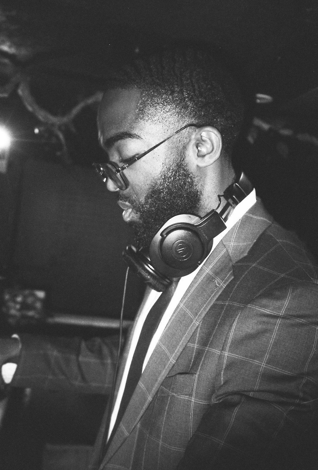 At the decks in a suit and tie, headphones round the neck